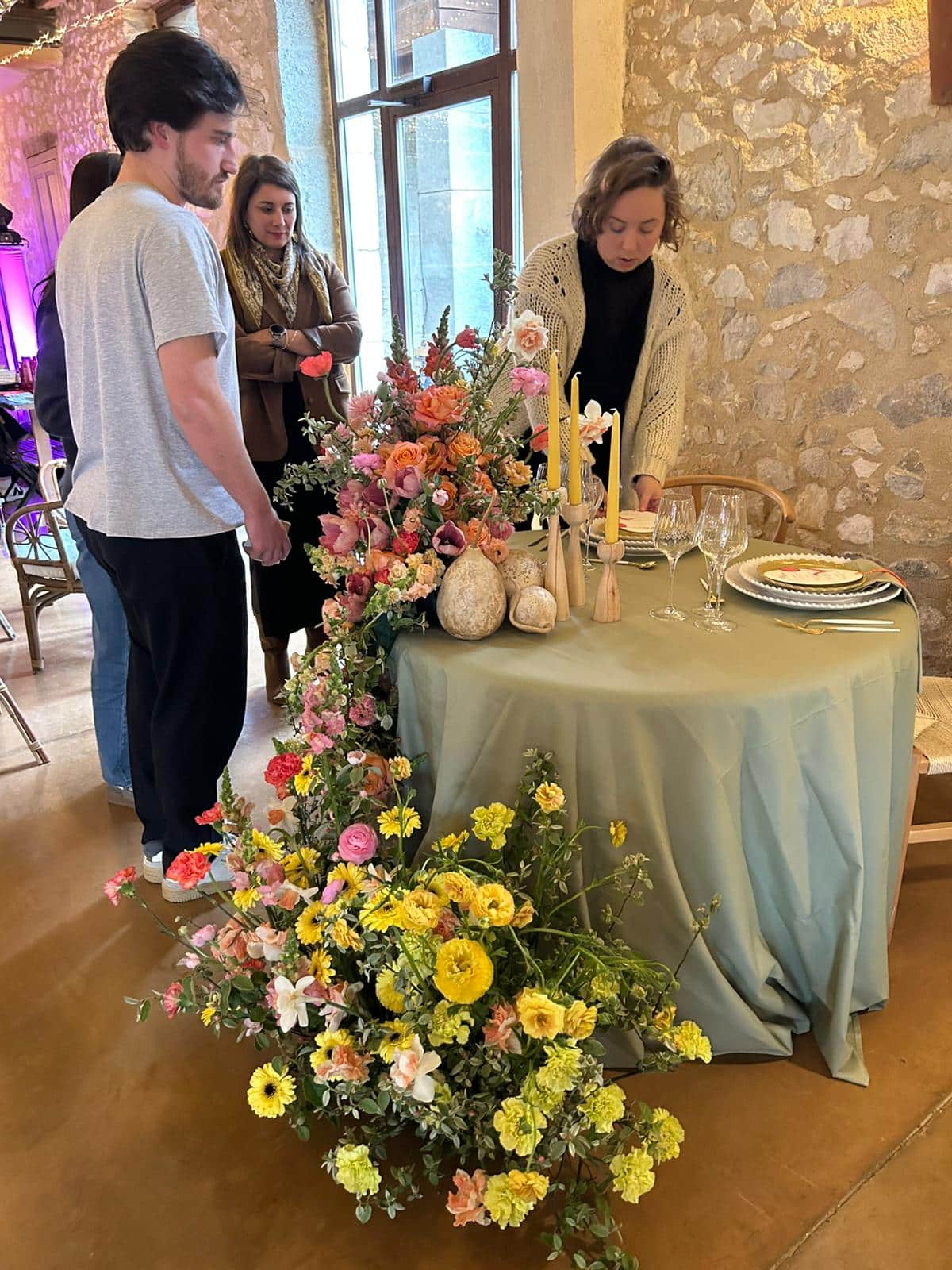 Décoration de table élégante avec arrangement floral en cascade rose et jaune et chandelles pour un événement raffiné.