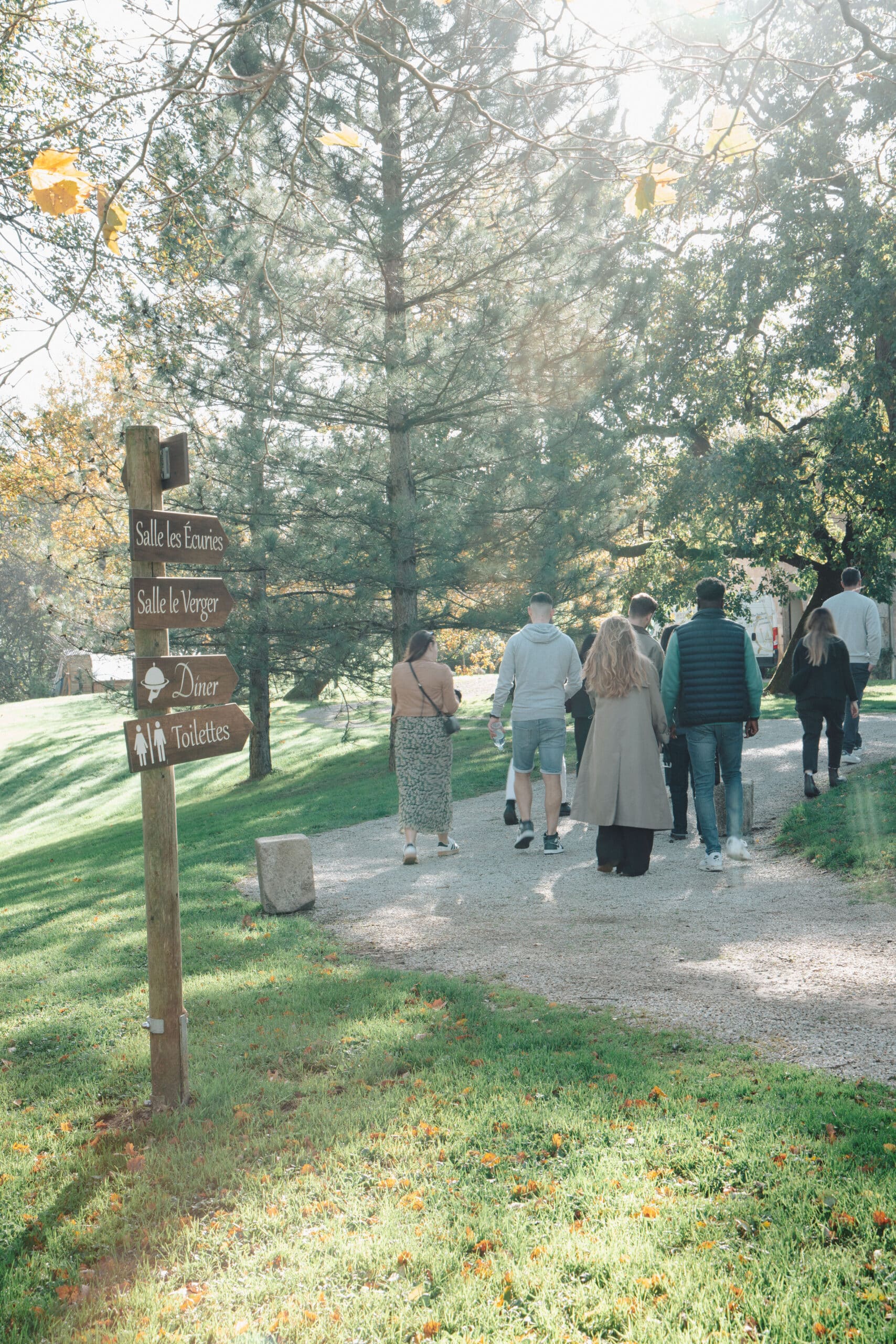 Groupe marchant vers les salles Écuries et Verger. Panneau bois indiquant Diner, Toilettes, Verger et Écuries.